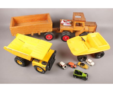 A wooden toy tractor with cart along with a metal matchbox dumper and similar plastic example, etc.  