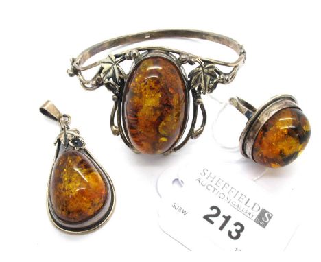 A Hallmarked Silver Amber Coloured Bangle, NHJ, the large amber coloured stone, oval collet set between decorative foliage su