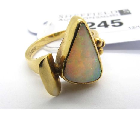 An 18ct Gold Opal Set Dress Ring, of Modernist design, the kite shaped stone rubover set to scroll style shoulder with beaded