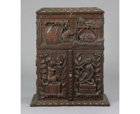 AN ANTIQUE CARVED OAK BLACK FOREST PIPE-SMOKERS CABINET WITH ALL-OVER ANIMAL AND FOLIAGE DECORATION, ENCLOSED BY A HINGED LIF