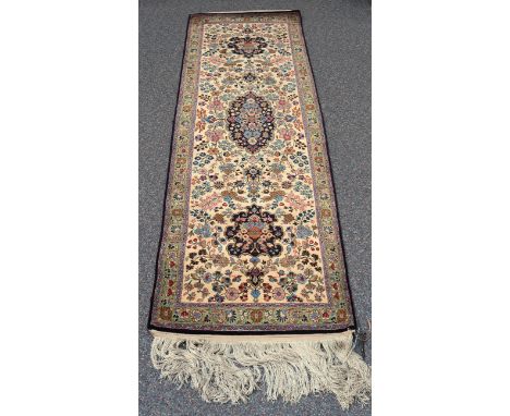 A Kashmir part silk runner, late 20th century, the ivory field with a lobed foliate medallion and matching palmettes supporte
