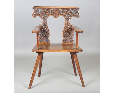 An early 19th century Continental walnut sgabello armchair, the shaped back finely carved with a shield and scrolls, the soli