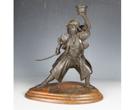 A modern bronzed cast resin figure of a samurai warrior, supporting a candle sconce aloft, raised on a shaped plinth, 40cm.Bu