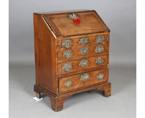A small George III oak bureau, the fall flap above four drawers with elaborate brass handle plates, height 96cm, width 72cm, 