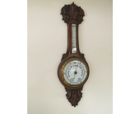 A carved oak wall barometer with a white enamel dial and mercury thermometer box good condition. Length 90cm