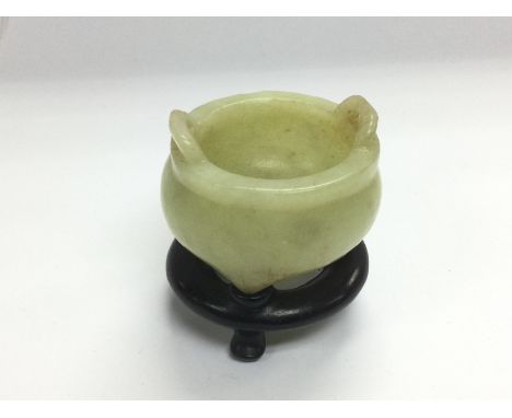 A small jade pot on a carved hardwood stand, total approx height 6cm. Shipping category B.