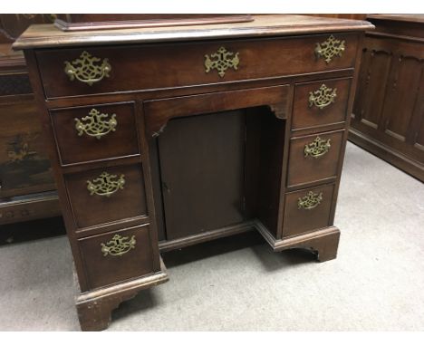 A Georgian mahogany knee hole desk the regular top above seven drawer cupboard to centre on bracket feet