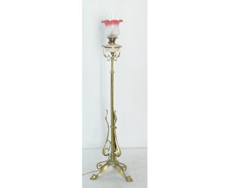 Late Victorian brass extending standard lamp, converted to electricity, with a cranberry tinted and etched glass shade, over 