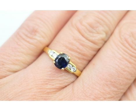 Sapphire and diamond ring, in 18ct yellow gold, oval cut sapphire in a four claw mount, approx. 0.25ct, bordered with two sma