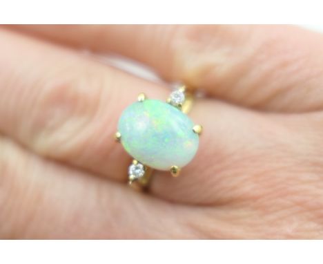 White opal and diamond ring, the cabochon opal of approx. 11mm x 8mm, set within two small brilliants in 18ct yellow gold cla