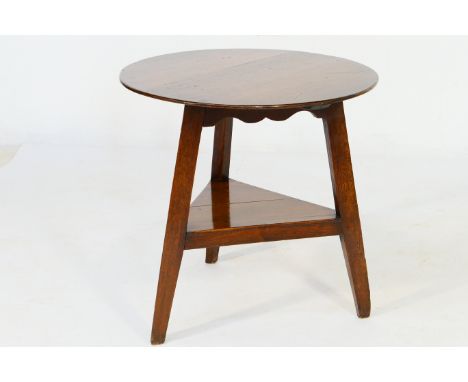 Oak cricket table, early 19th Century, circular top over three supports with a platform shelf beneath, 77cm diameter