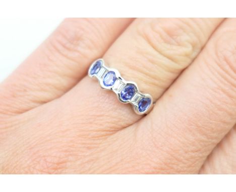 Tanzanite and diamond half hoop ring, in 18ct white gold, having four oval cut tanzanites dispersed with three small baguette