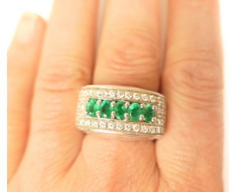 Emerald and diamond pave ring in 18ct white gold, set with five oval cut emeralds, claw and channel set, within a pave of sma