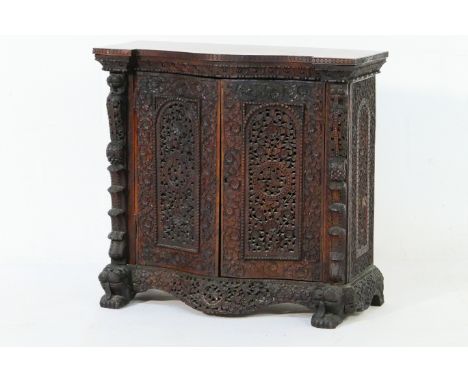 Indian carved rosewood serpentine cabinet, late 19th Century, profusely carved with trailing flowers and foliage, fitted with
