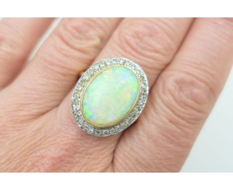 Opal and diamond cluster ring, the large cabochon opal of approx. 17mm x 12mm, collet set in 18ct yellow gold and bordered wi