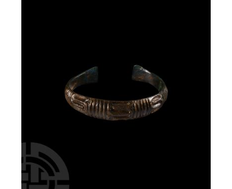 9th-11th century A.D. Of penannular form, vertical grooves and snaking lines to the bezel, tapering arms with ornamental notc