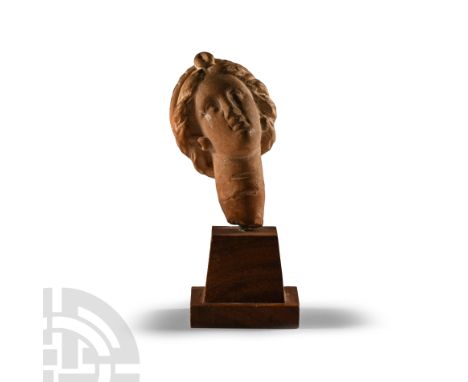 4th-3rd century B.C. With a delicately modelled face and full lips, hooped earrings visible from beneath her hair; the hair w