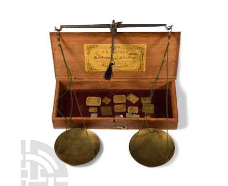 1894-1897 A.D. A wooden box with hinged lid and gummed label, enclosing a weighing scale and two pans; weights in various den
