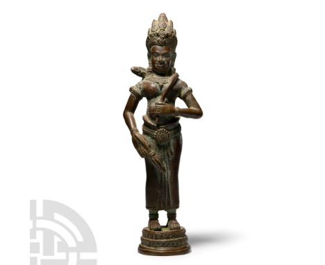 Circa 18th-19th century A.D. Standing on an integral decorated plinth base and holding two lotus flowers wrapped around her s