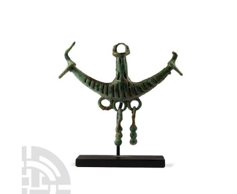 Circa 8th century B.C. Pendant with crescentic body and beast-head finials, vertical upstand with loop finial, three loops be