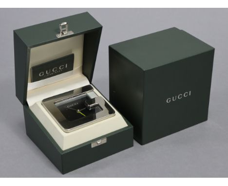 A Gucci desk clock with polished ‘G’ face &amp; brushed-finish body, black   dial &amp; quartz alarm movement, 3¾” wide; in o