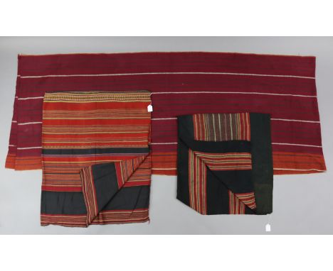 An Asian long textile panel of burgundy &amp; ochre ground, 14’4” x 2’10”; together with two other similar textiles, 4’7” x 4