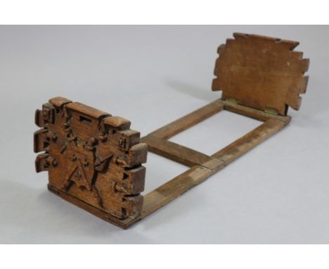 A Victorian carved oak book trough with coat-of-arms to each shaped folding end; 20” long x 6½” high.