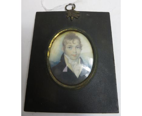 An early 19th Century oval miniature portrait of a young man on ivory panel and in original black rectangular frame with meta