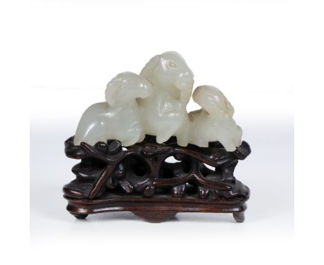 White jade pebble Chinese, 19th-20th Century pierced and carved as a group of goat and two young, on wood stand pierced and c