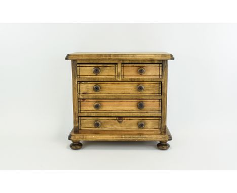 A Small Apprentice Table Top Chest of Drawers In Light Wood. Features 2 Small Drawers Above 3 Long Drawers, Raised on 4 Circu