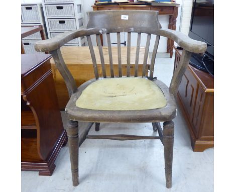 A 1920s unfinished, oak framed office chair with a scrolled bar crest and horseshoe shaped back, on square laths, the upholst