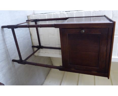 A Georgian mahogany pot cupboard, enclosed by a panelled door, raised on ring turned, spindled legs, united by lath stretcher