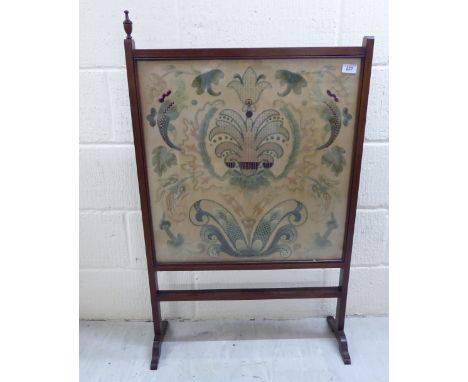 An early 20thC mahogany framed firescreen, set with a glazed, embroidered silk tapestry panel, raised on platform feet  39''h
