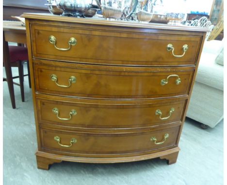 A modern Georgian style yew wood finished bow front dressing chest, the four graduated drawers with lacquered brass bail hand