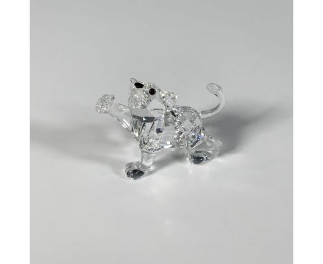A dazzling precision-cut figure of a baby lion with its arm stretched out, adorned with a black nose and iridescent eyes. Par