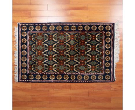 A stunning rug in shades of blue, green, red, and cream, adorned with intricate diamond, floral, and snowflake like patterns,