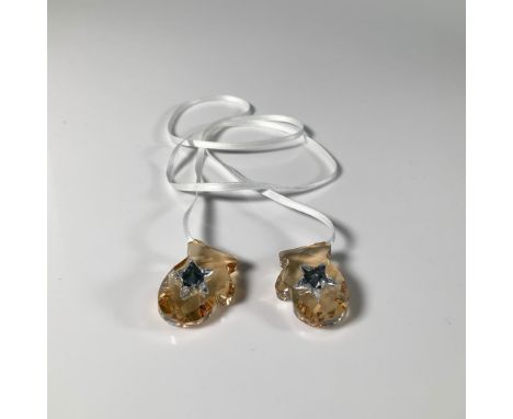 This lovely holiday decor features two small beige-colored crystal mittens with star accents, hanging from a white ribbon. Sw