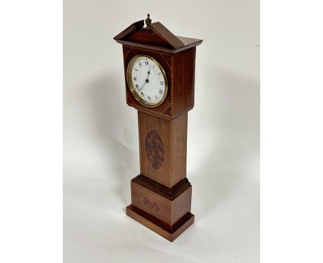 An Edwardian mahogany inlaid miniature pedimented longcase style table clock with white circular enamel dial and roman numera
