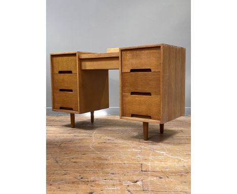A mid century light oak dressing table / knee hole desk, the centre lifting to a storage well, above six drawers, raised on t