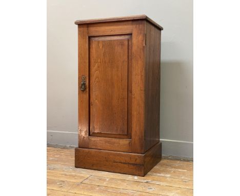 An Edwardian walnut bedside cupboard, fitted with a fielded panelled door enclosing a shelf, raised on a skirted base. H78cm,
