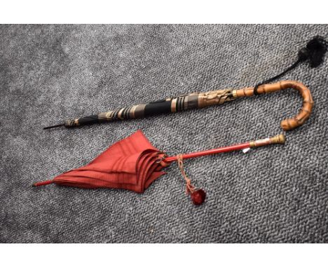 A vintage parasol having enamel pictorial plaque to handle and gold accents. Also included is a black and beige umbrella.