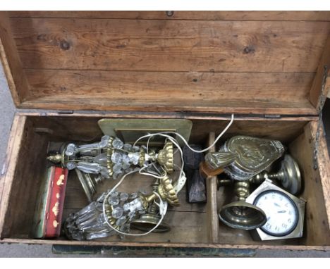 A pine trunk and contents including a Deco clock, brass candlesticks etc.