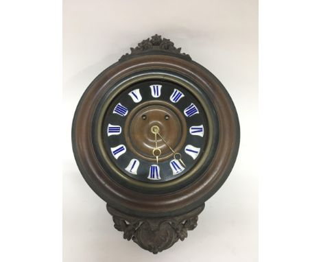 A carved wood wall clock with enamel Roman numeral dial