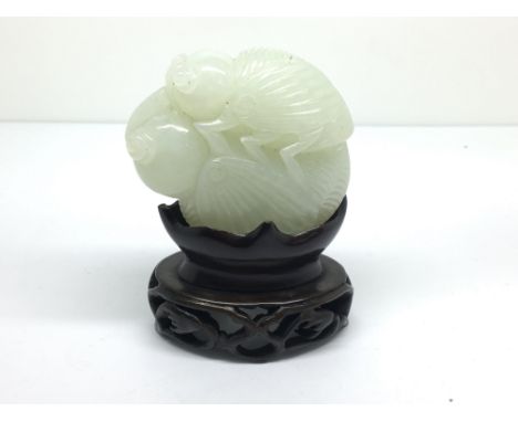 A small carved, light green jade model of a grasshopper on a flower bud, with carved wooden stand