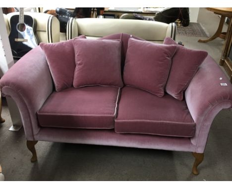 A Pink draylon upholstered two seater sofa with a shaped back and drop in cushions, with scroll arms and cabriol legs, with a