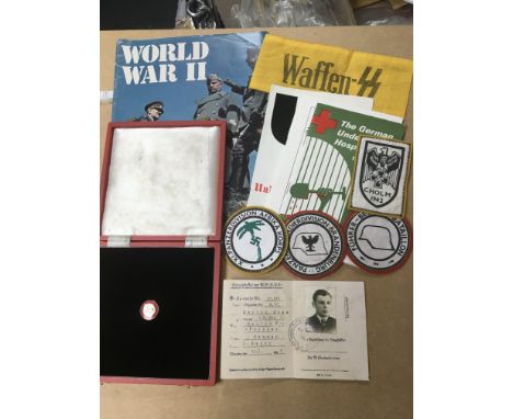 A collection of WW2 related German/Nazi items including an enamel badge, Waffen armband and brochures.
