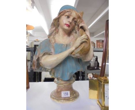 A plaster bust of a female with a string instrument.