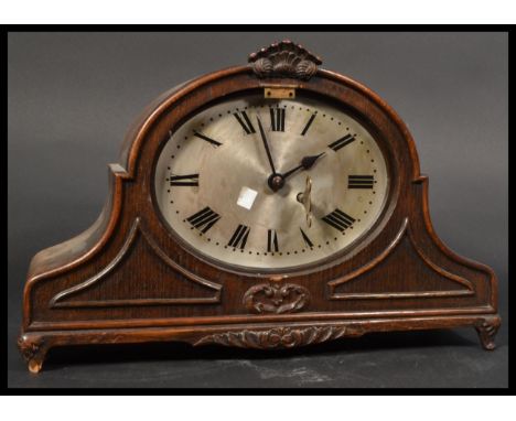 An Edwardian oak arched cased 8 day mantel clock having oval silvered dial with roman numeral chapter ring