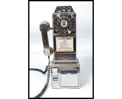 An American style contemporary coin operated wall telephone by Wild and Wolf having a ring dial and phone to side.&nbsp;Measu