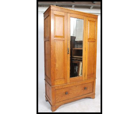 A Victorian oak panelled wardrobe having a single mirrored door raised on a deep long drawer base with bracket feet.